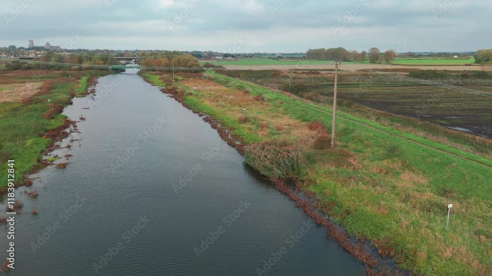 A calm Ely river flowing through green fields with a bridge and horizon in view A calm Ely river flowing through green fields with a bridge and horizon in view