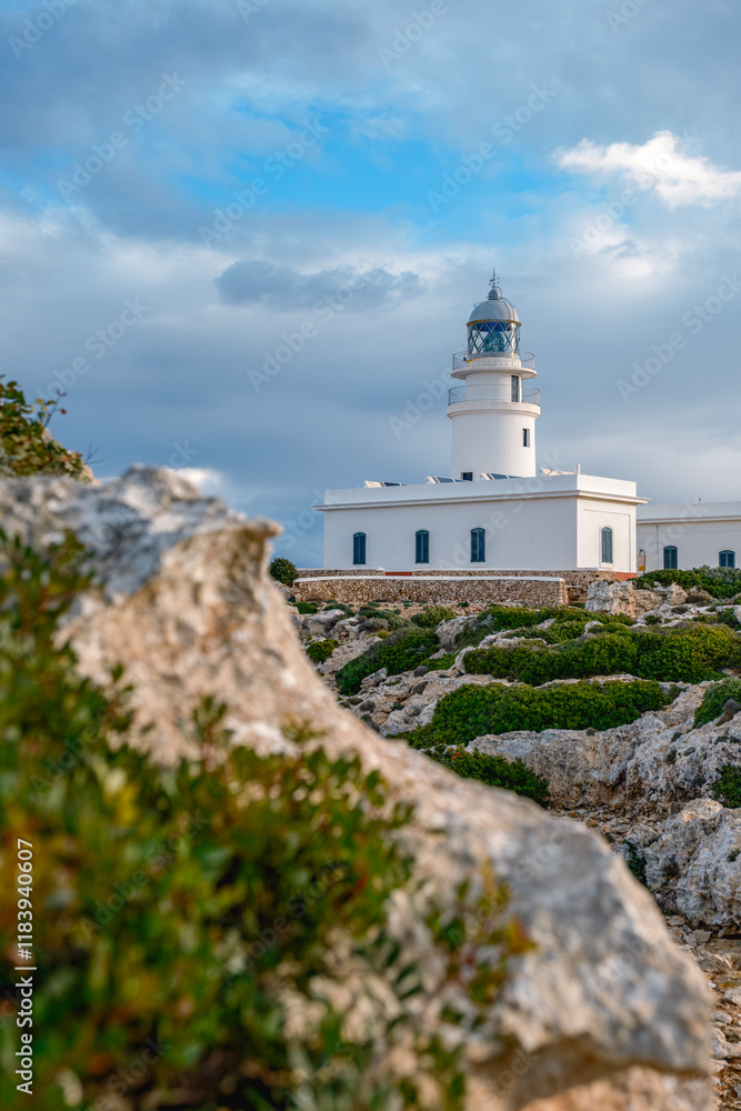 View from the rocks off the coast of the Cap de Cavalleria lighthouse on the north coast of Menorca (Balearic Islands) during a summer day with dramatic cloudy sky, Minorca, Spain.
