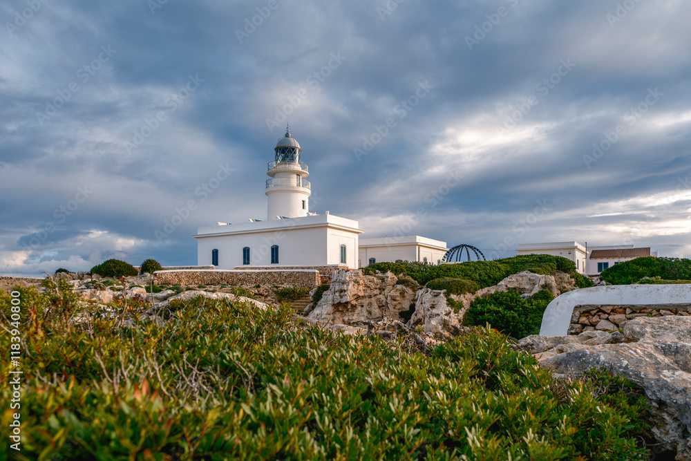 View from the rocks off the coast of the Cap de Cavalleria lighthouse on the north coast of Menorca (Balearic Islands) during a summer day with dramatic cloudy sky, Minorca, Spain.