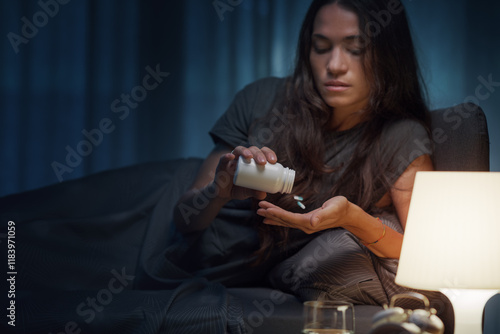 Fotografija Young woman taking medications at night