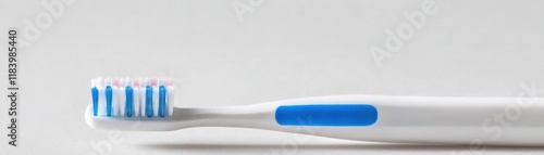 A close-up of a toothbrush with blue bristles on a minimalist background symbolizes daily oral hygiene and self-care routines. photo