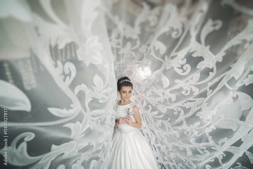 A woman is standing in front of a white curtain with a flower in her hand. The curtain is flowing and the woman is the center of attention