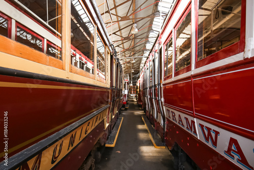 Two vintage red trams in depot, showcasing classic design and vibrant colour photo