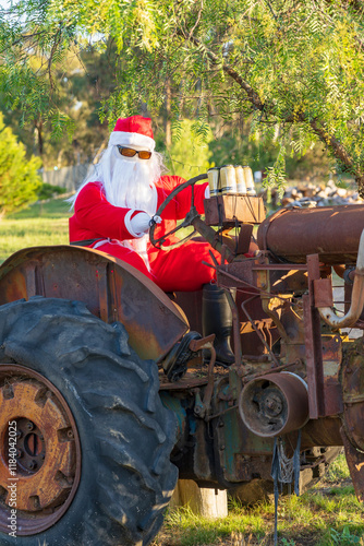 A mannequin in a santa costume sitting on an old rusty tractor photo