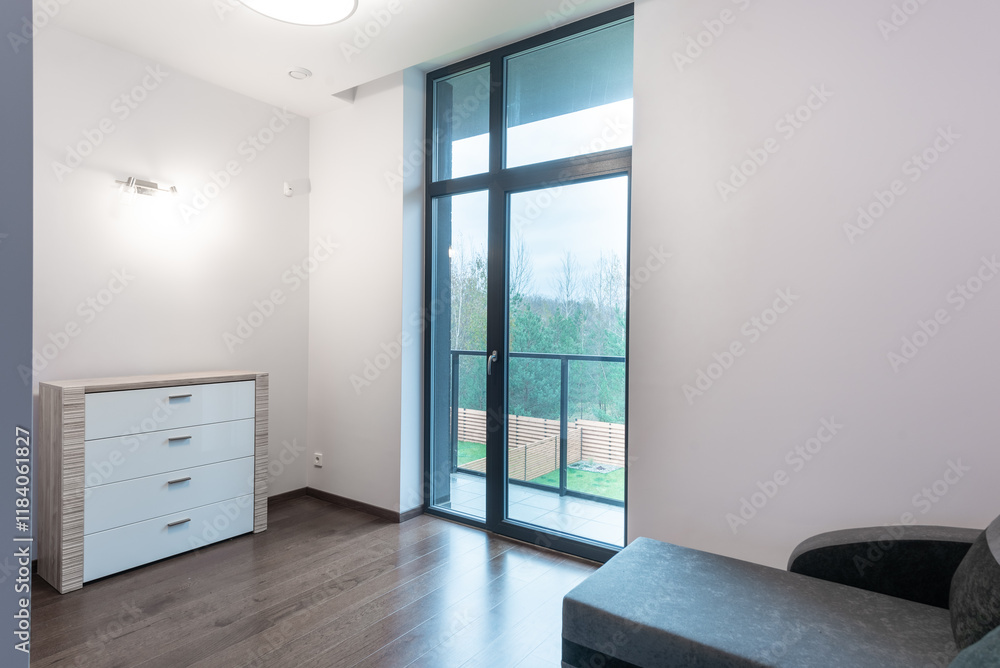 Obraz premium Modern bedroom with large window overlooking a tranquil landscape. A dresser and chaise lounge complete the serene atmosphere. Home Interior
