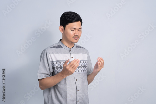 Muslim man praying for Ramadan with calm expression on isolated white background