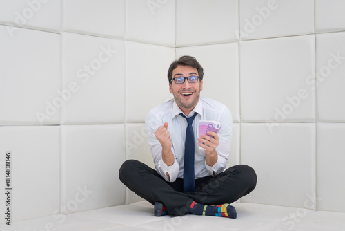 Happy businessman in formal wear sitting in a white room in a mental hospital	 photo