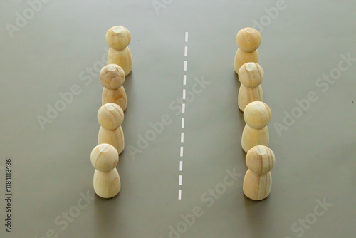 фотографія Two groups of wooden figures standing in rows, with a dividing line symbolizing boundaries or team separation