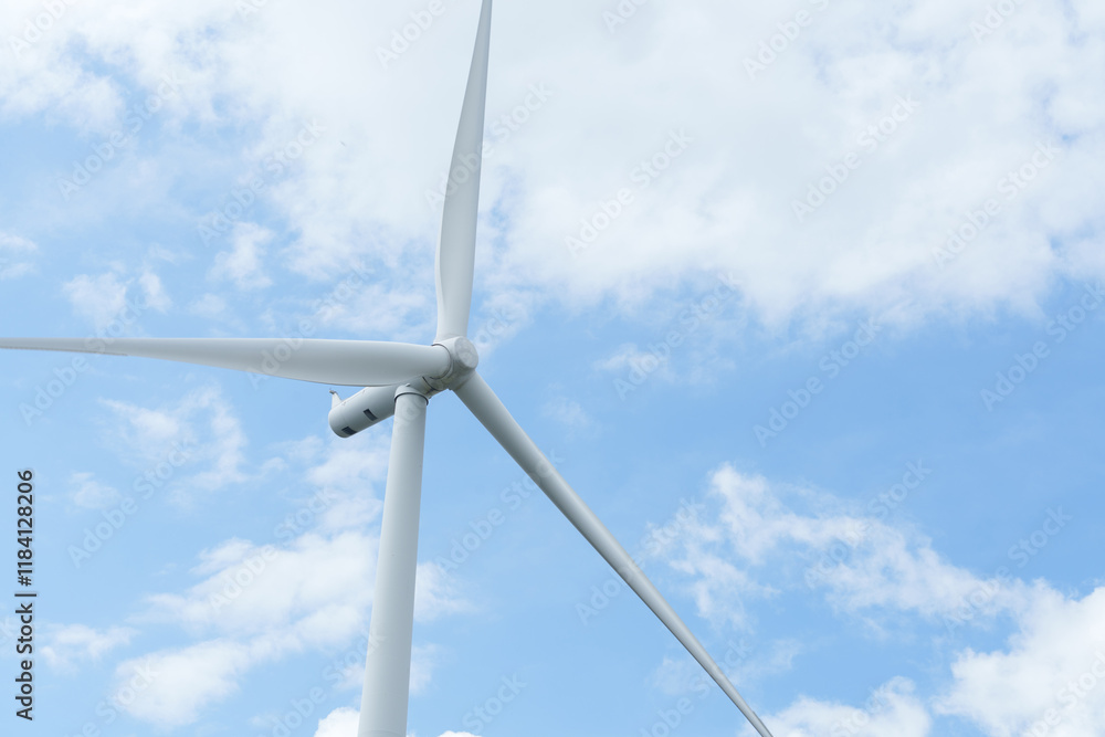 A close-up shot of a wind turbine standing tall against a backdrop of wispy white clouds in a bright blue sky A close-up shot of a wind turbine standing tall against a backdrop of wispy white clouds in a bright blue sky