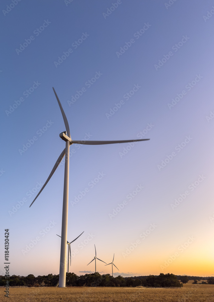 four towering white wind turbines on farming land at dusk four towering white wind turbines on farming land at dusk