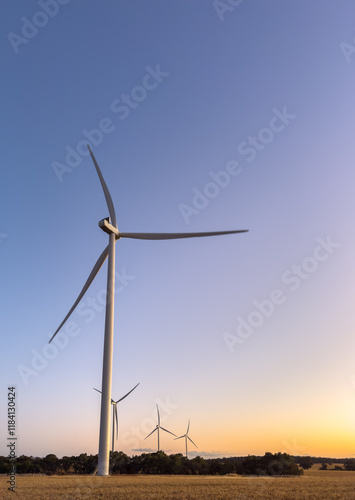 four towering white wind turbines on farming land at dusk photo