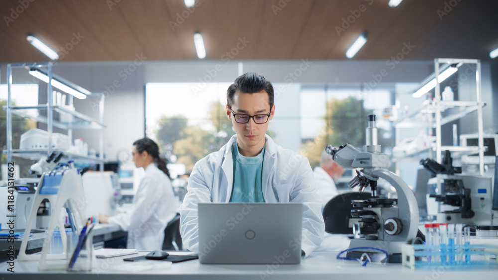 Genetic Research Scientist Working on a Laptop Computer in an Applied Science Laboratory. Portrait of a Handsome Young Multiethnic Lab Engineer in White Coat at Work Genetic Research Scientist Working on a Laptop Computer in an Applied Science Laboratory. Portrait of a Handsome Young Multiethnic Lab Engineer in White Coat at Work