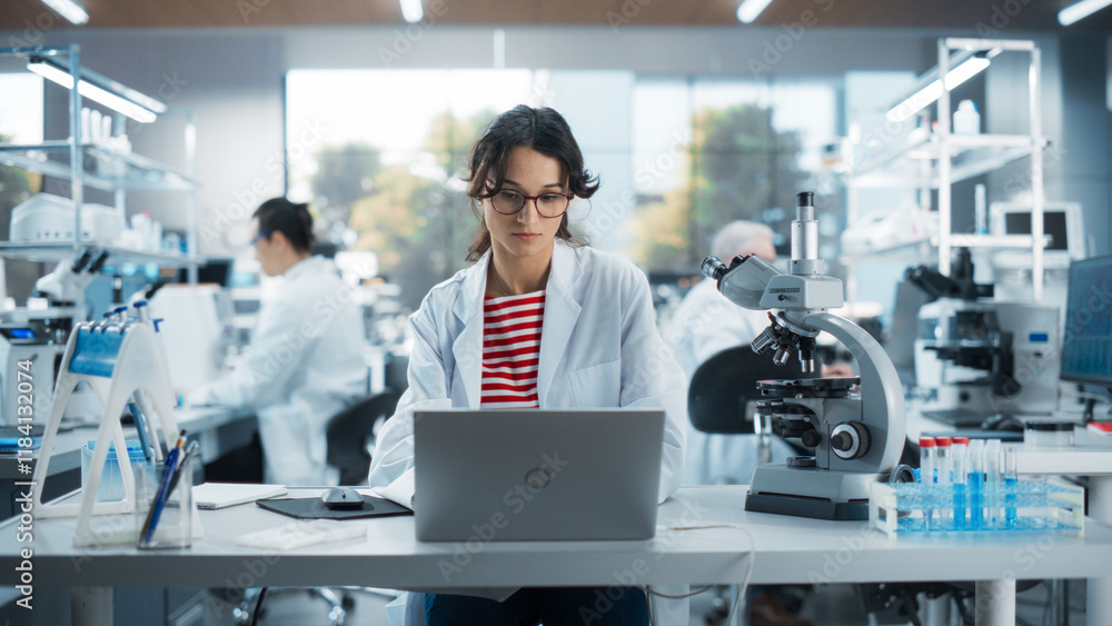Portrait of a Smart Female Student Working on Laptop on a Research Project in School. Medical Research Scientist Looking at Biological Samples Under a Microscope in an Applied Science Laboratory Portrait of a Smart Female Student Working on Laptop on a Research Project in School. Medical Research Scientist Looking at Biological Samples Under a Microscope in an Applied Science Laboratory