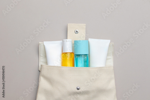 An artistic flat lay display of colorful skincare and cosmetic products scattered around a bag. photo