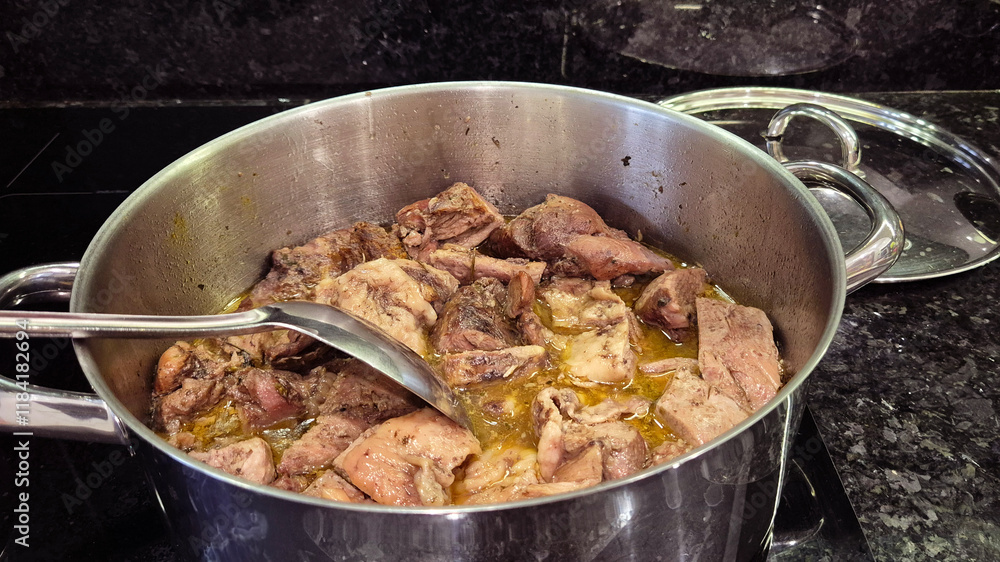 Turkey meat being stewed in a pot over an induction stove, with a spoon used to stir the dish. A hearty and flavorful meal prepared for a homemade family lunch or dinner. Turkey meat being stewed in a pot over an induction stove, with a spoon used to stir the dish. A hearty and flavorful meal prepared for a homemade family lunch or dinner.