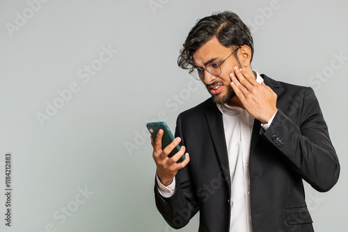Fotografie Upset sad Indian businessman use smartphone typing browsing, play game, loses, surprised by sudden lottery results bad fortune loss fail unlucky news