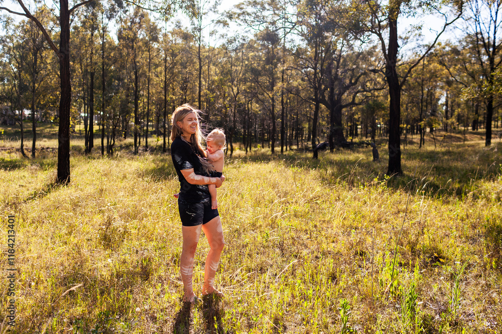 Aboriginal woman with her eight month old baby boy together in Australian bushland Aboriginal woman with her eight month old baby boy together in Australian bushland