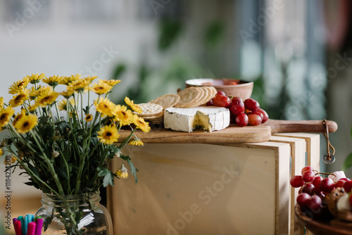 Vase of flowers and cheese platter on table photo