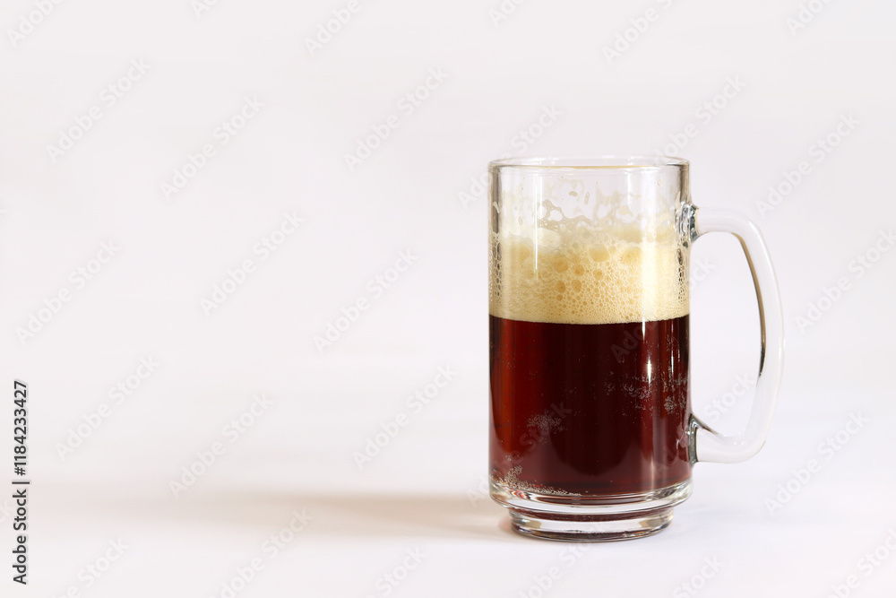 Kvass in a glass, light background. Glass of dark beer or kvass with foam in a glass on a light gray background. Traditional beer mug with a handle. Close-up on a glass with a cool tasty drink Kvass in a glass, light background. Glass of dark beer or kvass with foam in a glass on a light gray background. Traditional beer mug with a handle. Close-up on a glass with a cool tasty drink