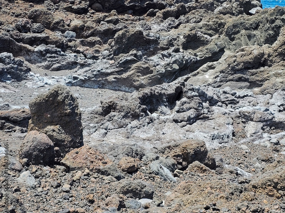 Des formations rocheuses volcaniques irrégulières et de teintes variées s'entrelacent, créant un relief accidenté et aride. Des formations rocheuses volcaniques irrégulières et de teintes variées s'entrelacent, créant un relief accidenté et aride.