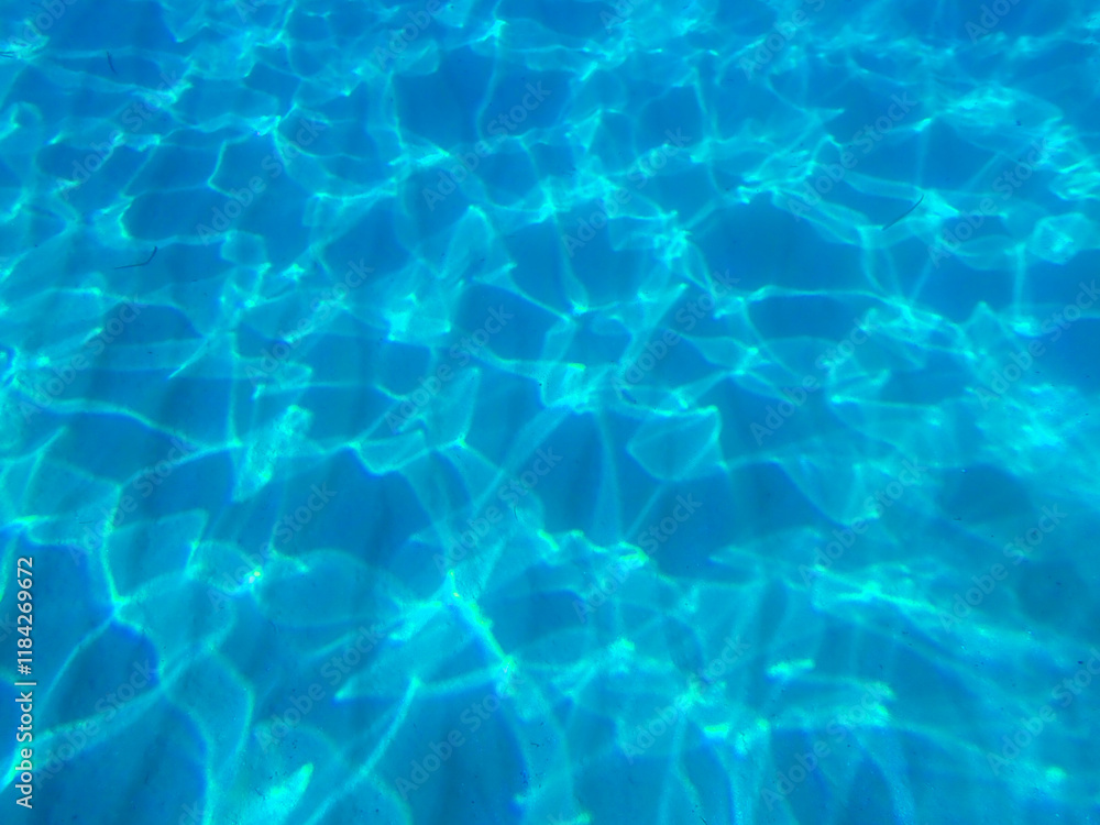 Blue water in the swimming pool with light reflections. Clear Water Caustic Texture, Clear Blue Turquoise Water Surface Shimmering in Sun on Sunny Day, Slow Motion. Blue Green Water in Pool. top view. Blue water in the swimming pool with light reflections. Clear Water Caustic Texture, Clear Blue Turquoise Water Surface Shimmering in Sun on Sunny Day, Slow Motion. Blue Green Water in Pool. top view.