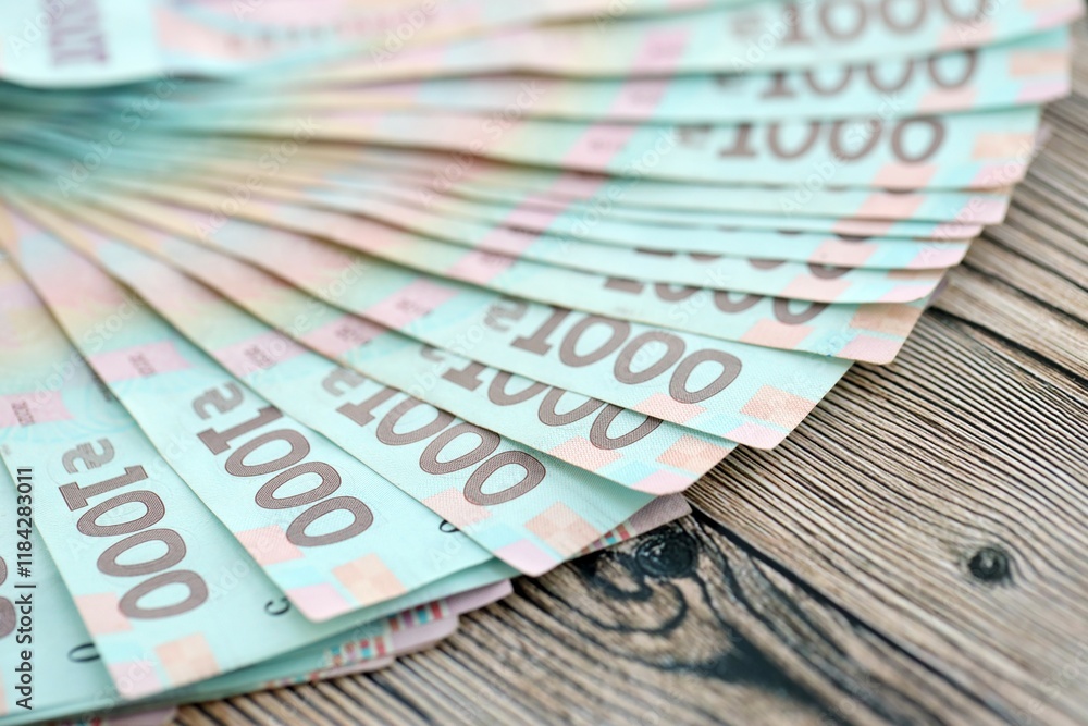 Fototapeta premium Big amount of ukrainian new one hundred hryvnia money bills with modern design on wooden background. Financial concept, business