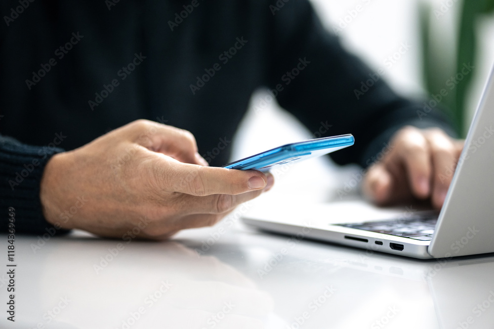 Closeup image of a male hands using smartphone and laptop. Boy working online, internet applications Closeup image of a male hands using smartphone and laptop. Boy working online, internet applications
