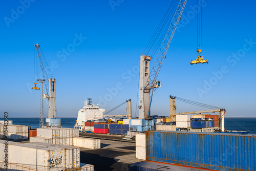 Obraz na płótnie Cargo port busy with loading a bulk carrier, port and deck cranes w salonie