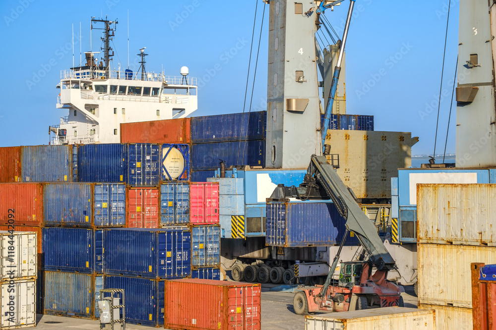 Reach stacker carry container along bulk carrier in cargo port on