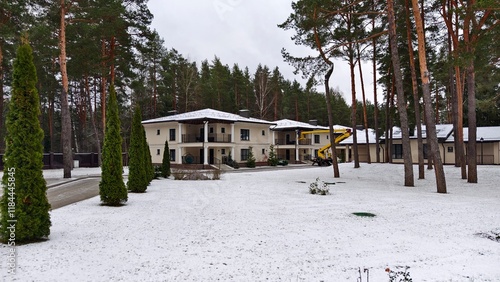 Next to the two-story building with columns is a special truck tower with a fenced-in platform raised up. Before Christmas, workers hang garlands with light bulbs on the houses. Nearby are thujas photo