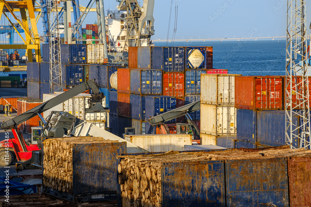 Stacked cargo and flat rack containers, cranes at work on sunny day in