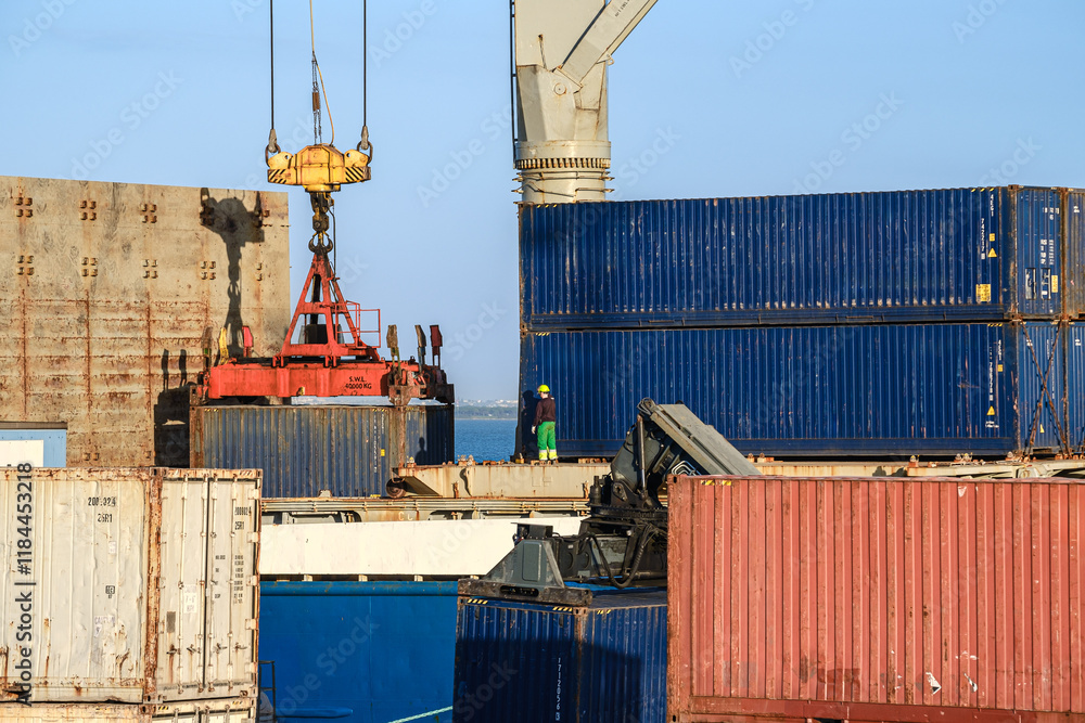 Workers handle crane loading cargo containers at a shipping terminal
