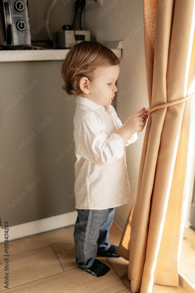 A little boy wakes up in the morning and opens the curtains in his room A little boy wakes up in the morning and opens the curtains in his room