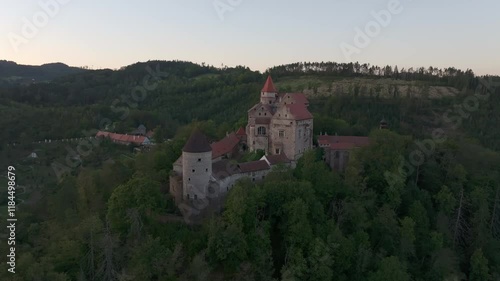 Aerial view of pernstejn castle at sunset surrounded by tranquil forest and hills, nedvedice, czech republic. photo