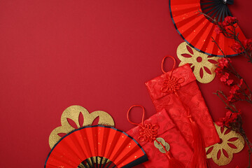 Chinese New Year celebration concept with red envelopes, paper fans, cherry blossoms on red background