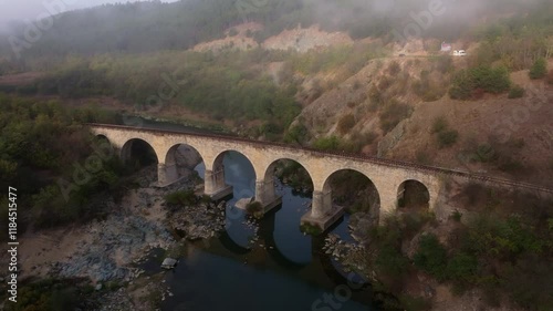 Aerial view of railway bridge over varbitsa river at sunrise surrounded by misty forest and mountains, Balabanovo, Bulgaria. photo