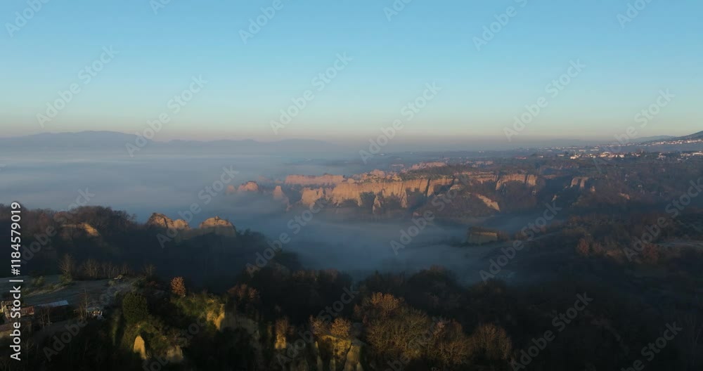 Aerial view of serene hills and a tranquil valley shrouded in fog at dawn, Tuscany, Reggello, Italy. Aerial view of serene hills and a tranquil valley shrouded in fog at dawn, Tuscany, Reggello, Italy.