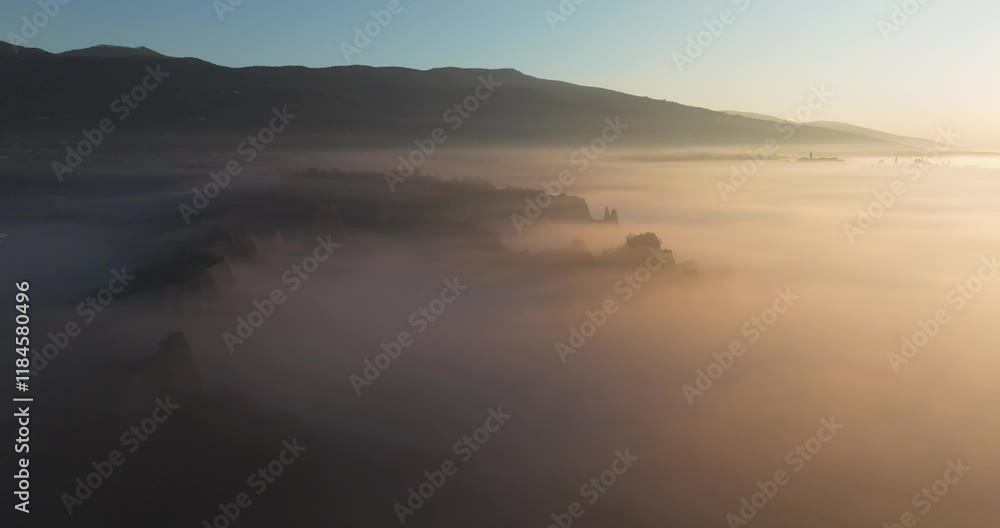 Aerial view of a beautiful foggy valley surrounded by serene mountains at sunrise, Tuscany, Reggello, Italy. Aerial view of a beautiful foggy valley surrounded by serene mountains at sunrise, Tuscany, Reggello, Italy.