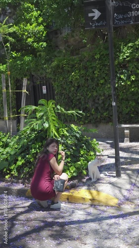 young latin woman caresses cat in the street