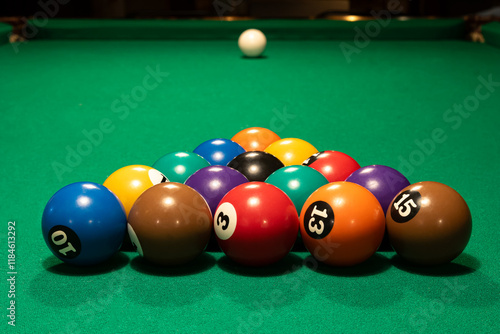 Conjunto de bolas de bilhar coloridas numeradas alinhadas como um triangulo em mesa verde de sinuca ao fundo a bola branca