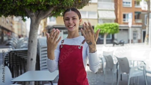 Wallpaper Mural Young woman making a come-hither gesture with her hands, standing on an outdoor cafe terrace in a city street. Torontodigital.ca