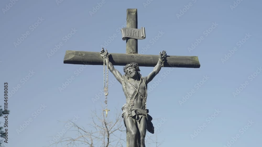 Crucifix statue of Jesus Christ on a weathered wooden cross under clear skies Crucifix statue of Jesus Christ on a weathered wooden cross under clear skies
