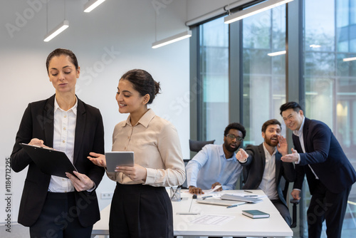 Photos Unethical behavior in the workplace, men discussing two women colleagues, inside the office at the workplace