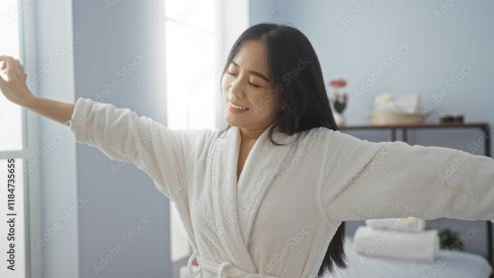 Woman relaxing indoors at a wellness center in china, wearing a white robe, showcasing contentment in a spa room bathed in soft light.