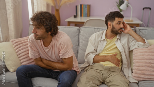 Fotografie Two men sitting together in a living room, expressing a tense moment, suggesting