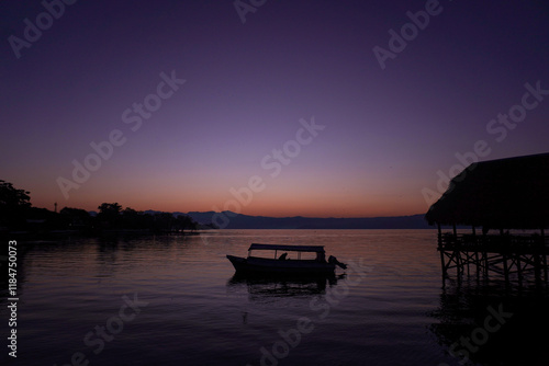 Amanecer en la Laguna de Catemaco con siluetas de una lancha y una palapa photo