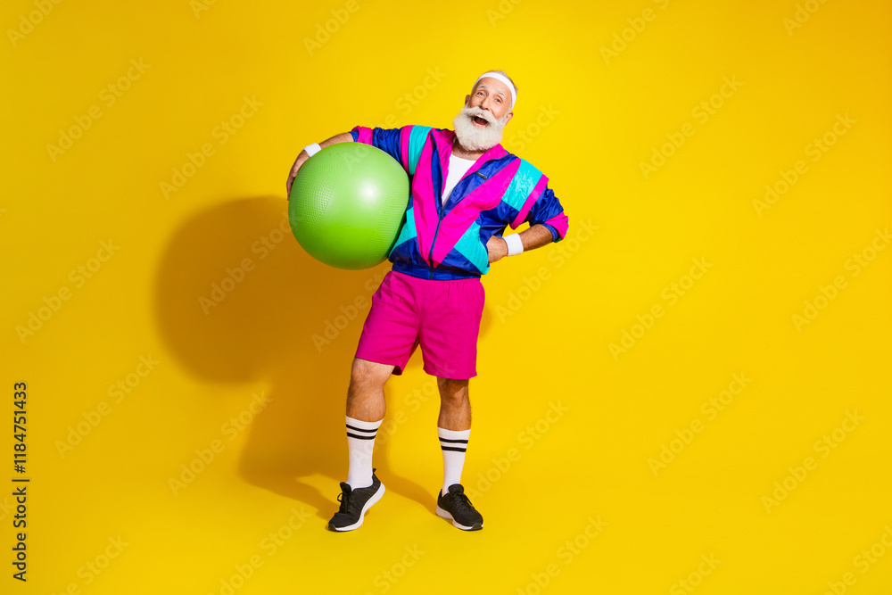 Obraz premium Full length photo of attractive funny retired sportsman retro sportswear holding fitball emtpy space isolated yellow color background