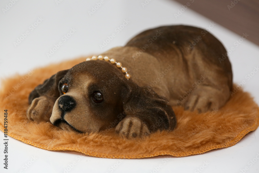 Cachorro de louça na estante para decorar o ambiente na cor marrom e deitado com carinha feliz.