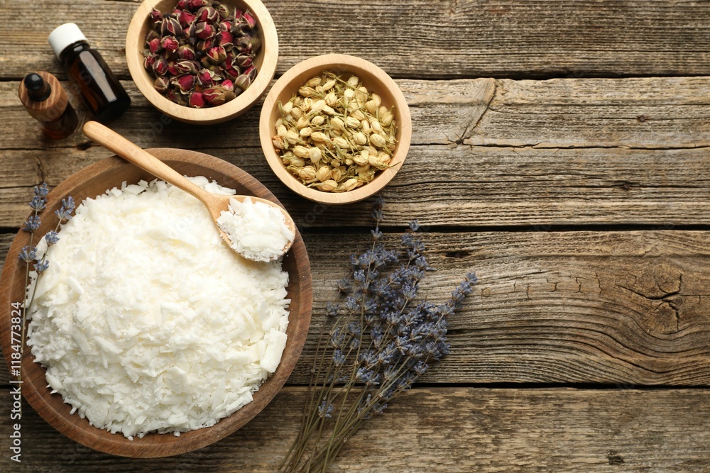 Soy wax in bowl and other different ingredients for making candles on wooden table, flat lay. Space for text