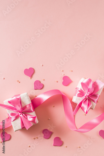 Pink hearts and gift box with ribbon on a light pink background